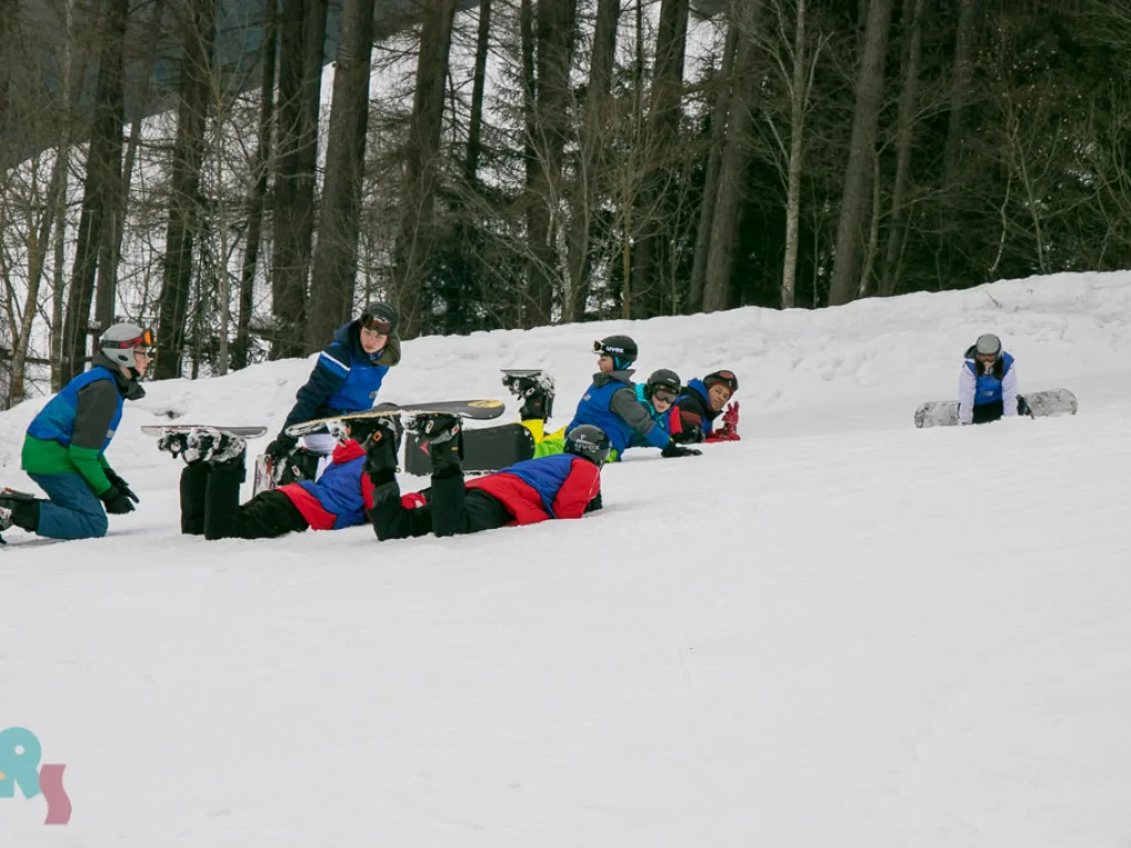 Snowboardgruppe macht am Pistenrand Pause.